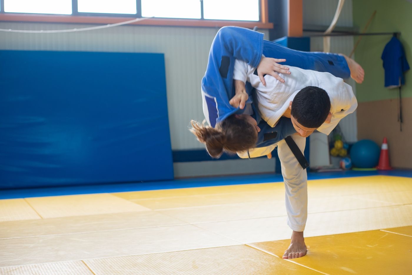 Judoka wirft die Partnerin in einer dynamischen Wurftechnik auf der Tatami